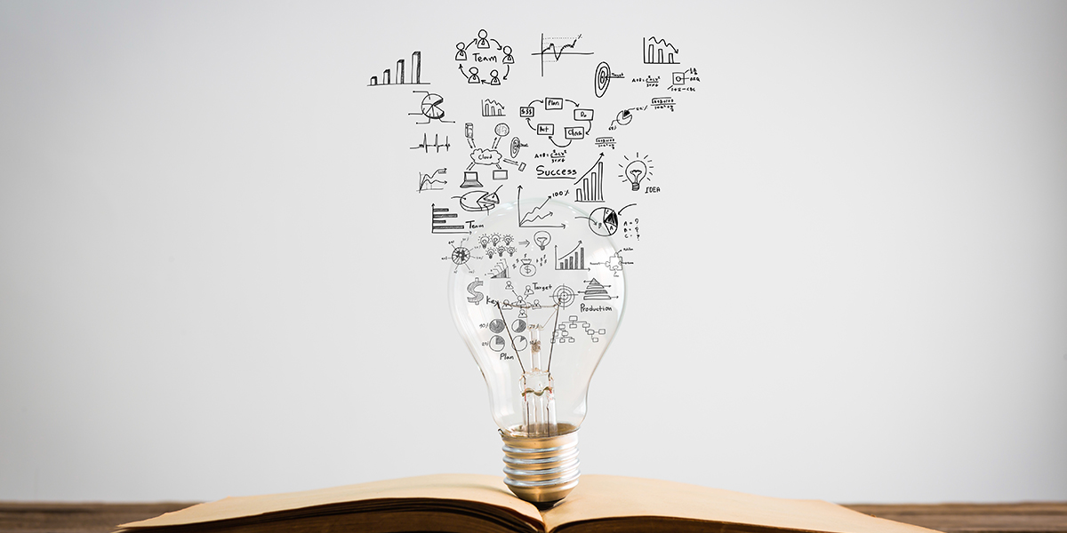 Image of lightbulb sitting on an open book, with sketches of infographics in the background